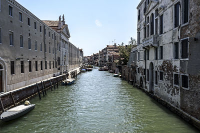 Canal amidst buildings in city against sky