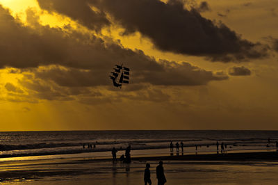 Silhouette people on beach against sky during sunset