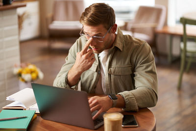 Young woman using laptop while sitting on table