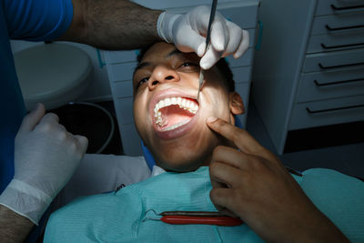 Dentist treating male patient in clinic