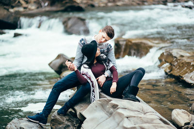 Rear view of couple sitting on rock