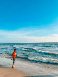 Rear view of woman walking at beach against sky