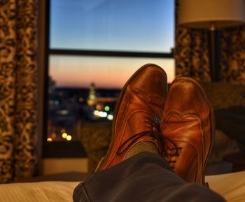 Low section of man wearing shoes sitting on bed at home