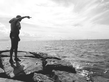 Full length of man on rock at beach against sky