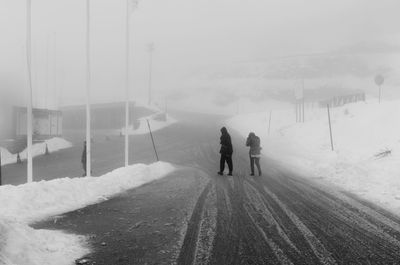 Rear view of people walking on snow covered landscape