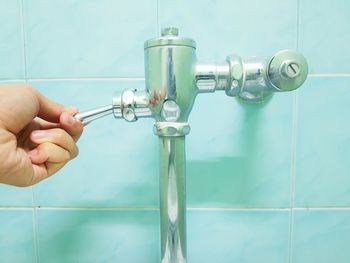 Close-up of hand flushing water in bathroom