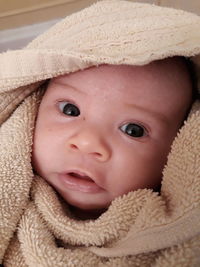 Close-up portrait of cute baby girl wrapped in towel