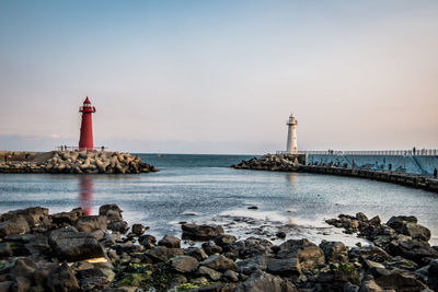 Lighthouse by sea against sky