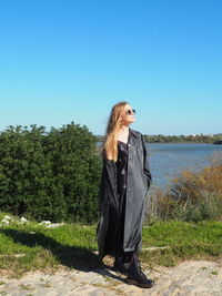 Woman standing by plants against clear sky