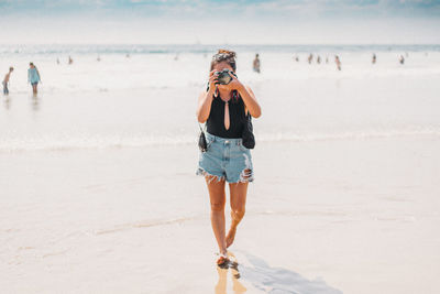 Young woman standing on beach against sky