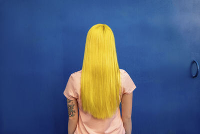 Rear view of woman standing against blue wall