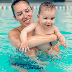 Close-up of mother holding toddler son in pool