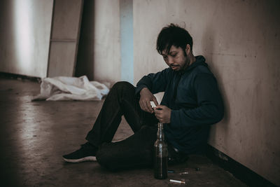 Side view of young man sitting on bed at home