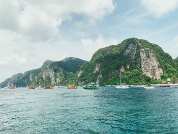 Scenic view of sea by mountain against sky