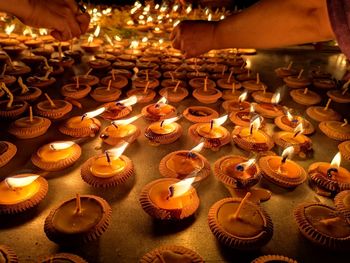 Cropped hands of people burning tea lights