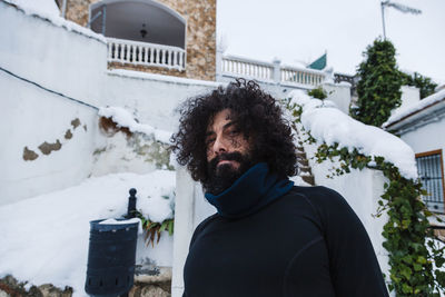 Carefree bearded mature man standing against building during winter