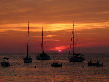 Sailboats sailing on sea against sky during sunset