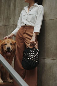 Midsection of woman with dog standing on staircase against wall