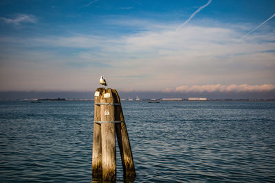 Lighthouse by sea against sky during sunset