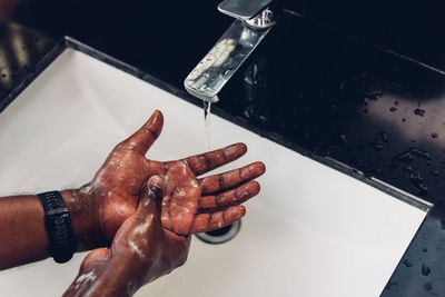 Close-up of man hand with faucet in water