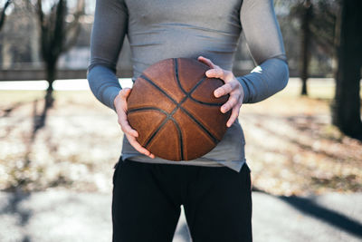 Midsection of man playing holding basketball