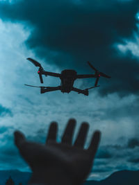 Low angle view of person hand against sky