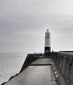 Lighthouse on calm sea against sky