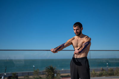 Portrait of young man standing against clear sky