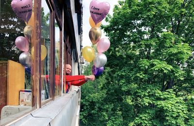 Rear view of woman with balloons balloon against trees