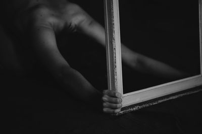 Shirtless person holding frame in darkroom