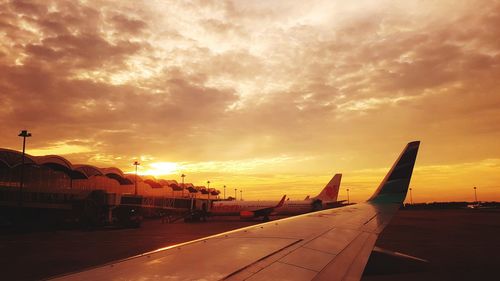 Airplane wing against sky during sunset