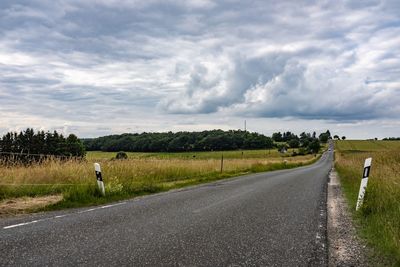 Road amidst field against sky