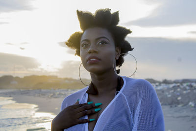 Portrait of young woman looking at sea against sky