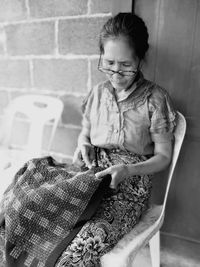 Full length of woman sitting against wall at home