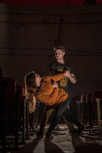 Young woman playing guitar while standing on stage