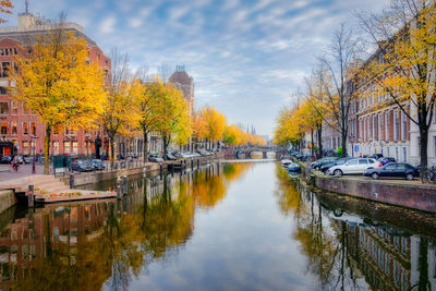 Canal amidst trees and buildings against sky during autumn