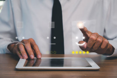 Midsection of man using mobile phone on table