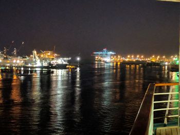 Illuminated harbor by sea against sky at night