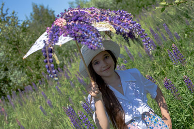 Portrait of smiling woman standing against purple flowering plants