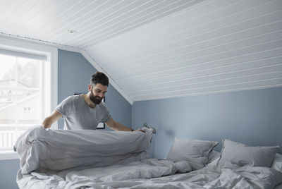 Happy man preparing bed at home