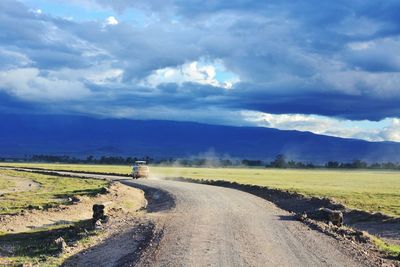 Road amidst agricultural field against sky