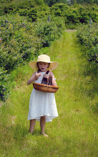 Girl picking berries in a white dress and straw hat