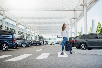 Young woman with bag crossing street at zebra crossing