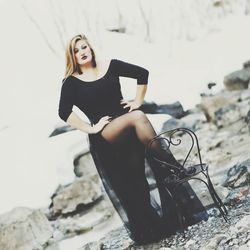 Portrait of beautiful dancer with chair standing outdoors