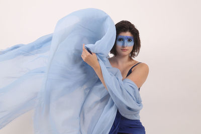 Portrait of female model with blue face paint against white background