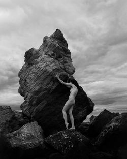 Low angle view of woman standing on rock against sky