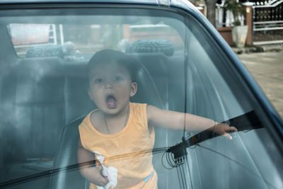 Portrait of boy in car seen through windshield