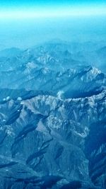 Aerial view of landscape and mountains against blue sky