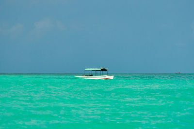 Boat sailing in sea against clear blue sky