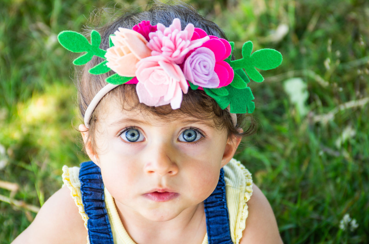 portrait, headshot, plant, childhood, flower, one person, child, flowering plant, real people, close-up, front view, cute, looking at camera, lifestyles, innocence, leisure activity, day, nature, body part, flower head, human face, outdoors, contemplation